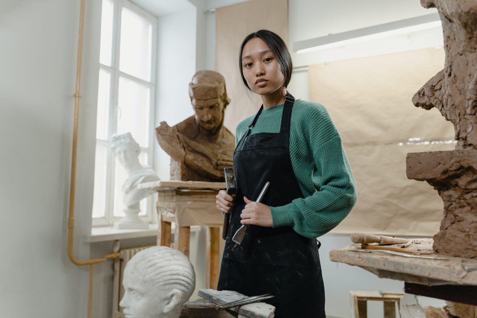 artist in studio with sculptures