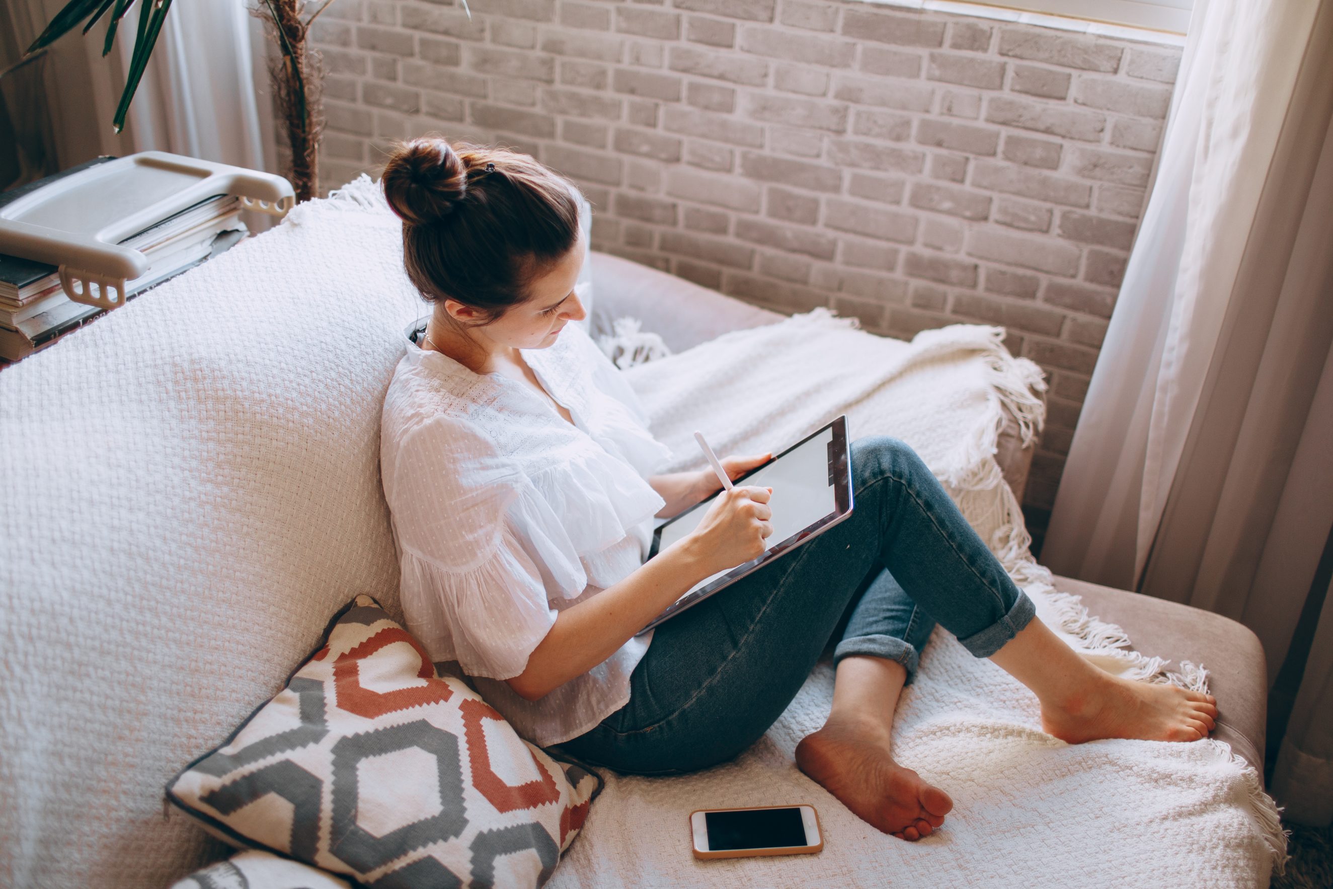 woman on couch working on ipad