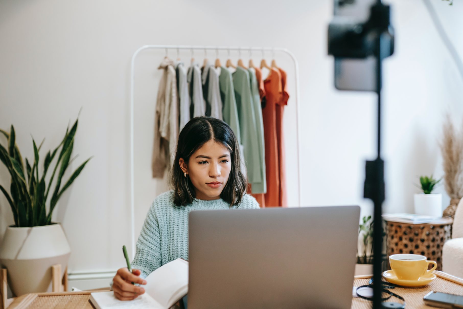 woman writing in notebook on laptop