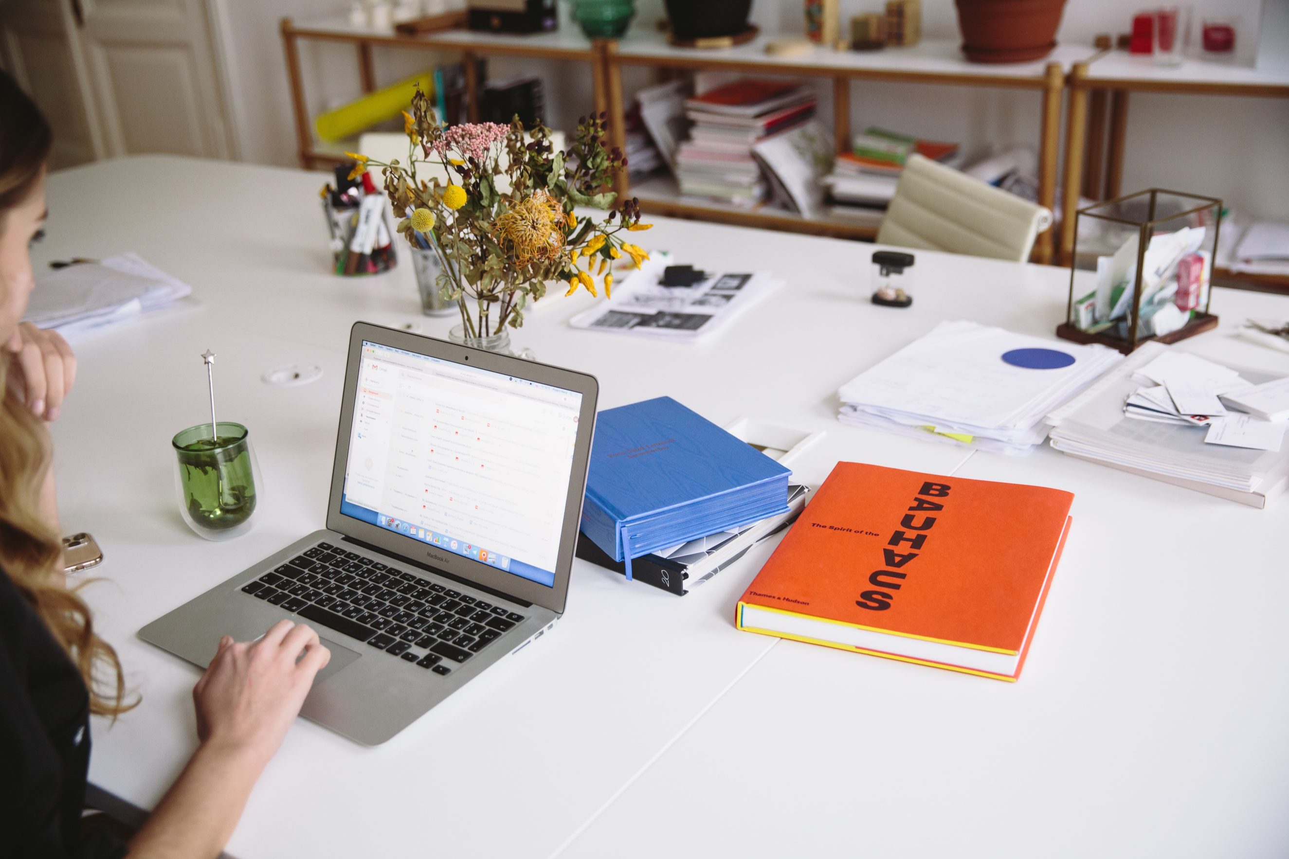 woman at table on laptop with books