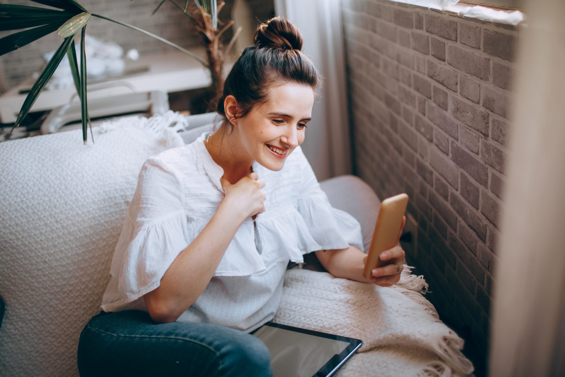 woman in white shirt looking at phone