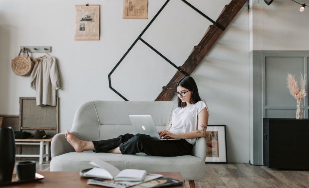 Woman sitting on couch using laptop.