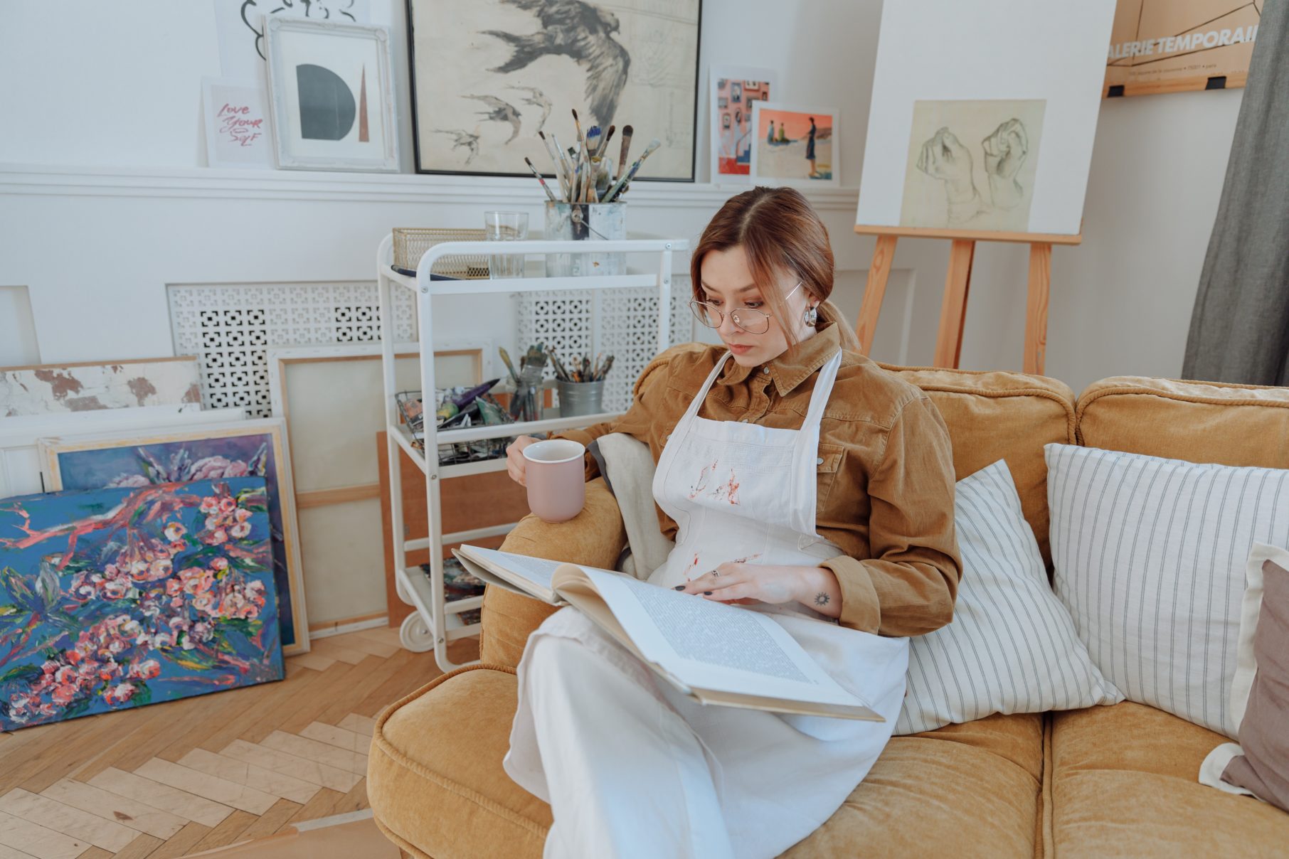 woman in smock reading a book in an art studio