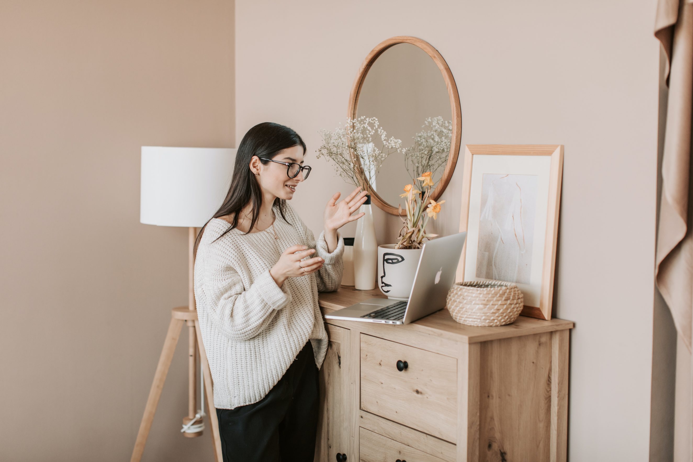 woman speaking to laptop camera on a dresser