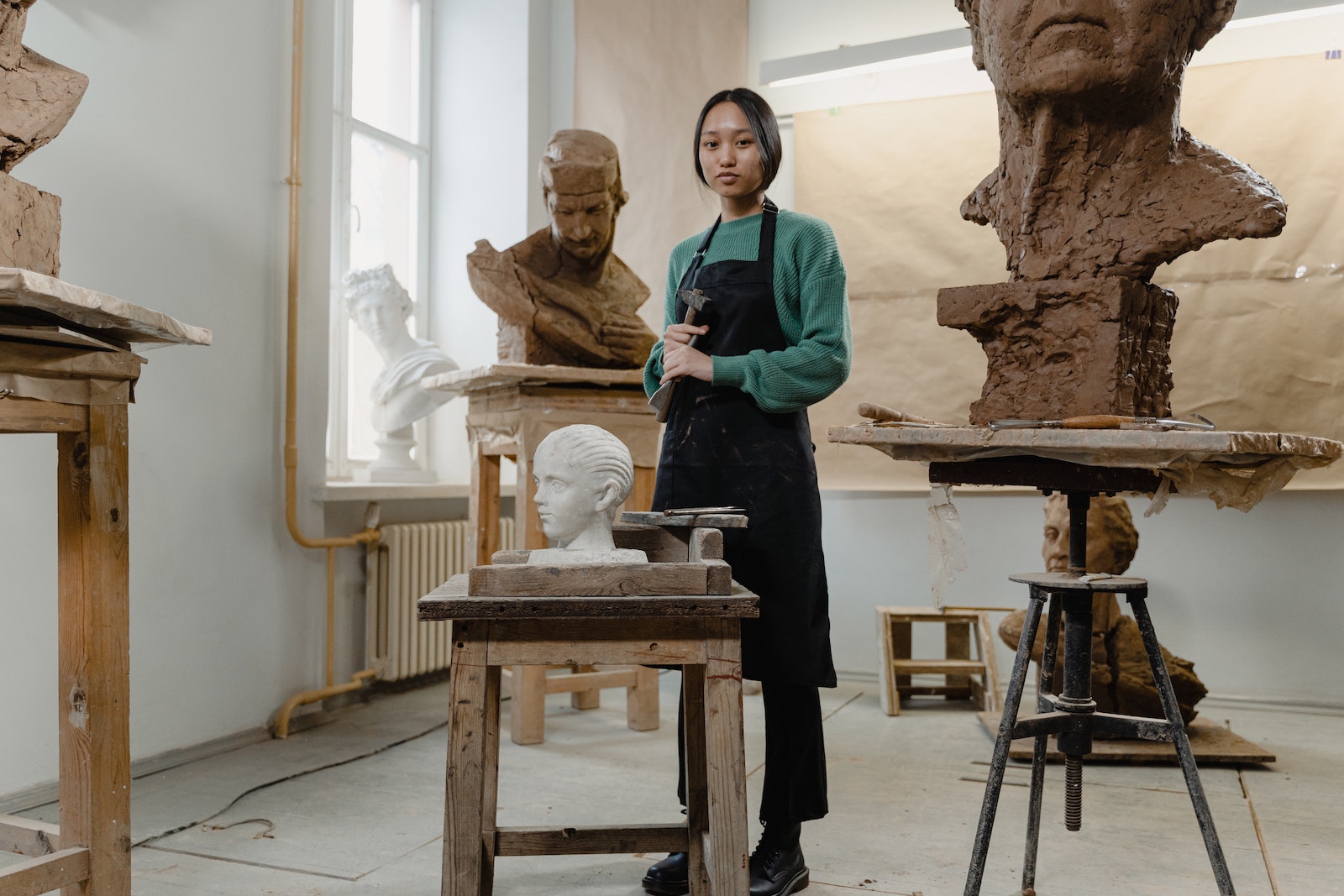 artist in studio with sculptures