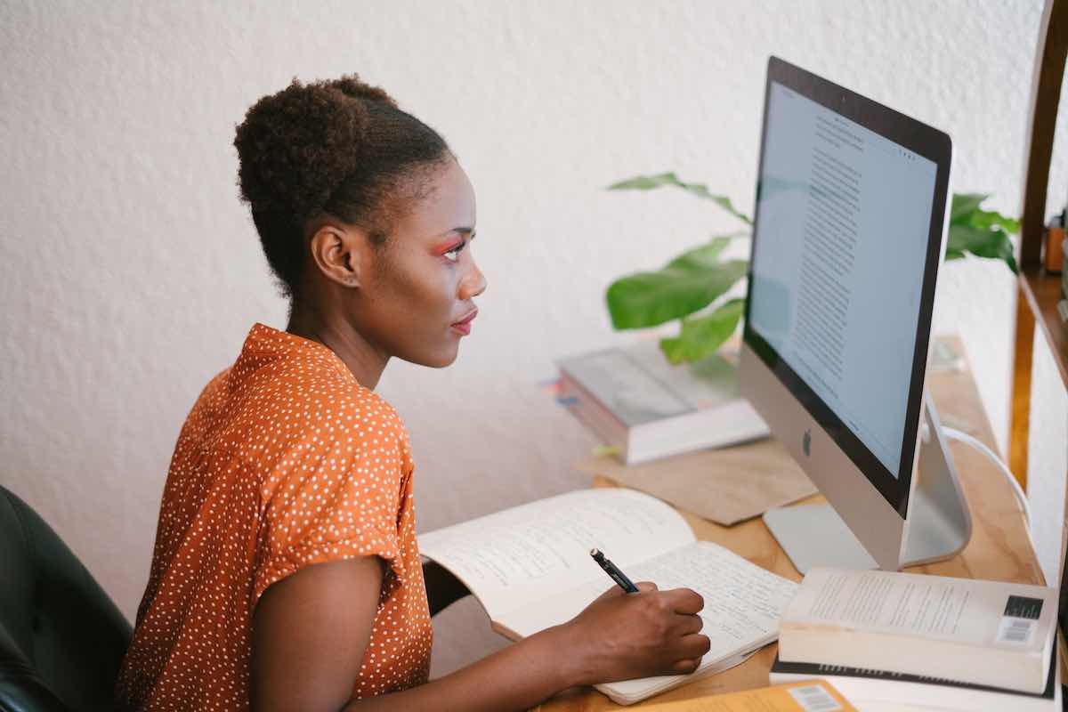 a person writing notes while reading on the computer